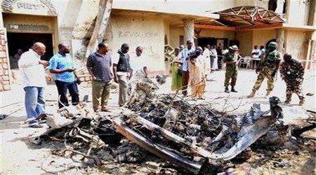 Security staff and onlookers view a car destroyed after a bomb set by Boko Haram terrorists killed 25 people attending Mass at St. Theresa Catholic Church in Madalla, Nigeria on Christmas Day, 2011. 