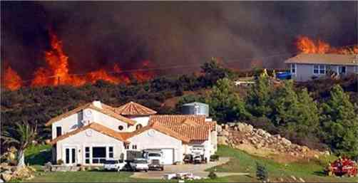 Firefighters try to protect two homes on a remote hillside in Bear Valley, south of Valley Center, Calif., on Monday. A state of emergency was declared in Los Angeles, San Bernardino, San Diego and Ventura counties as the fires laid to waste entire blocks of homes, closed major highways and roads, shuttered some schools, disrupted air travel nationwide, and literally sent people running for their lives.