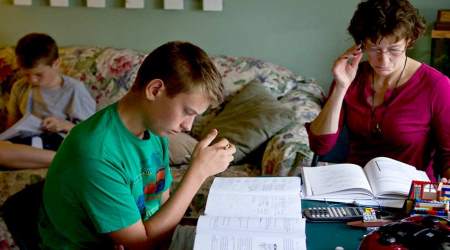 Shane McGregor, 12, left, and Bruce, 17, work in the living room on their coursework while their mother and teacher, Deanna, reviews more curriculum for her children's homeschooling.