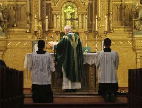 During the old-style Latin Mass, the priest faces the altar, not the people. Here, Monsignor Delbert Schmelzer celebrates Latin Mass at Holy Redeemer Catholic Church.