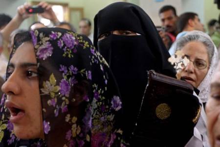 AN EGYPTIAN MUSLIM WOMAN HOLDS A CROSS WITH A KORAN AS SHE JOINS COPTIC CHRISTIANS AT THE VIRGIN MARY CHURCH IN THE IMBABA DISTRICT OF CAIRO ON JUNE 5, 2011. THE CHURCH HAD BEEN RESTORED AFTER IT WAS BURNED DURING CLASHES BETWEEN MUSLIMS AND CHRISTIANS.