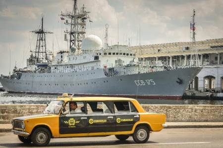 A Soviet-made Lada limousine passes by Russian Vishnya (also known as Meridian) class warship CCB-175 Viktor Leonov, docked, on February 26, 2014, at Havana harbor