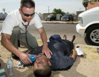 Physician's assistant Keith Williams, who works for Maricopa County Healthcare for the Homeless, treats Fernando Martinez for heat stress Thursday in Phoenix, Arizona. A record heat wave has led to the deaths of 18 people, most of them homeless, leaving officials scrambling to provide water and shelter to the city's transient population. 